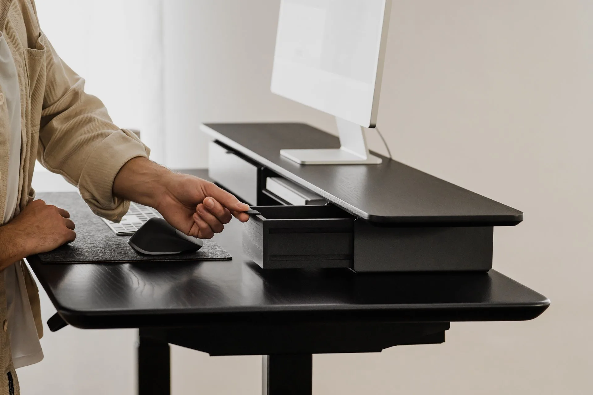 Person using a black Deskshelf Pro at a black desk