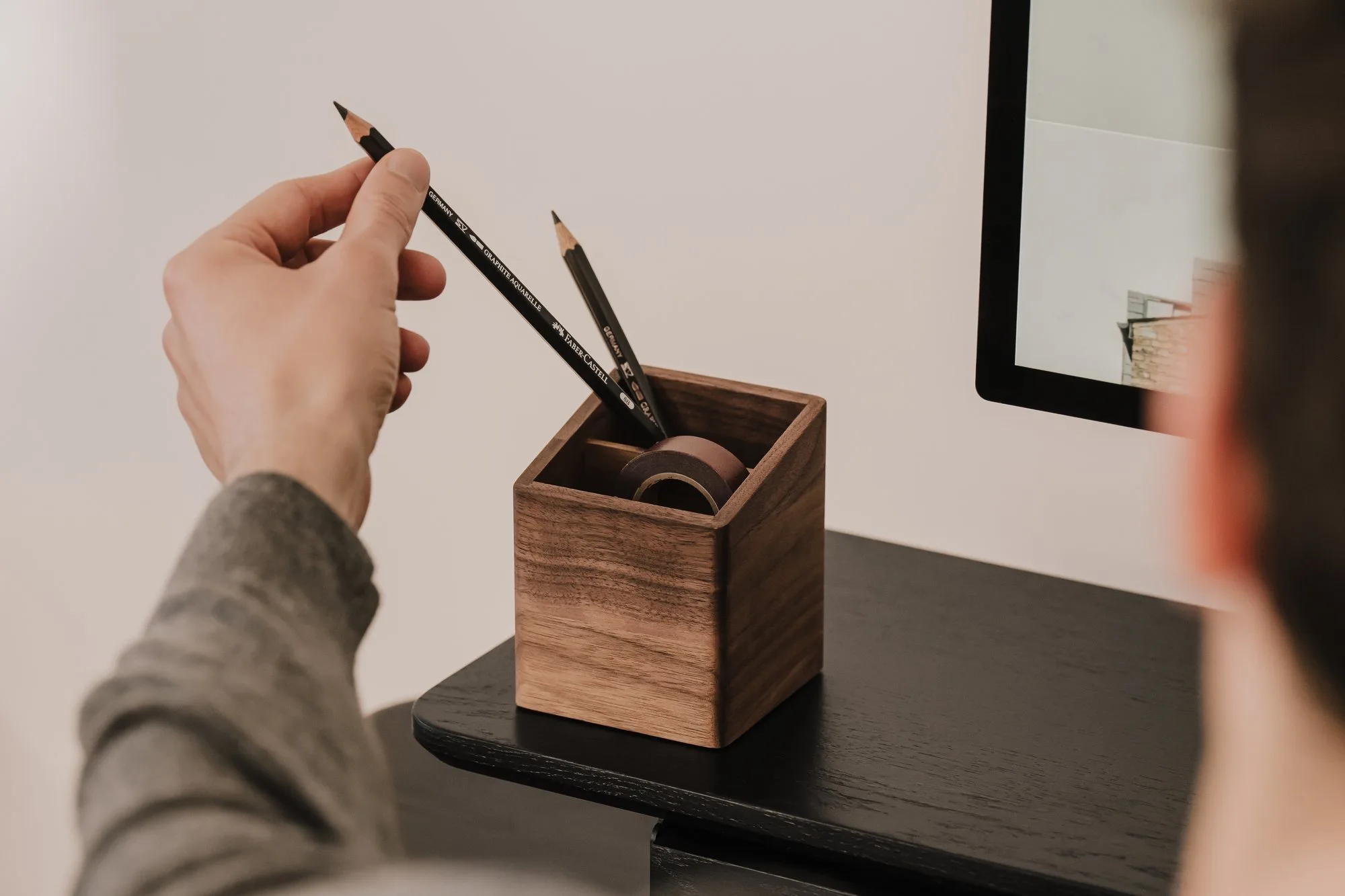 Hand taking a pencil from a walnut pen holder