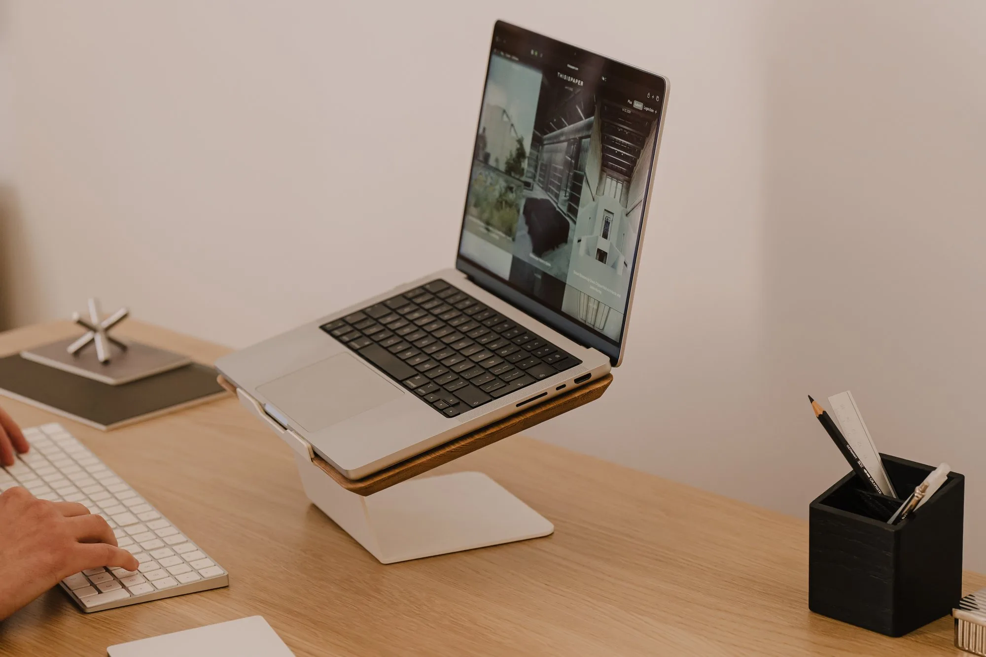 Laptop on an oak riser with a white base on a wooden desk