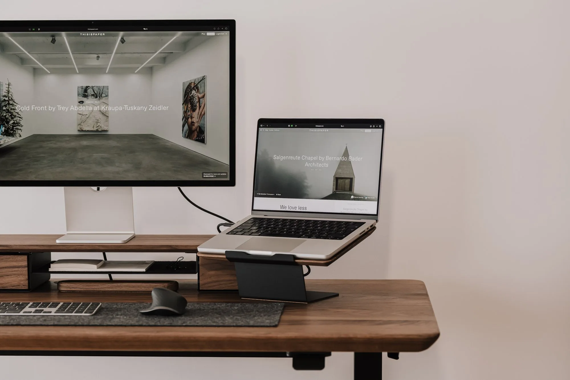 Laptop on a riser next to a monitor on a walnut desk
