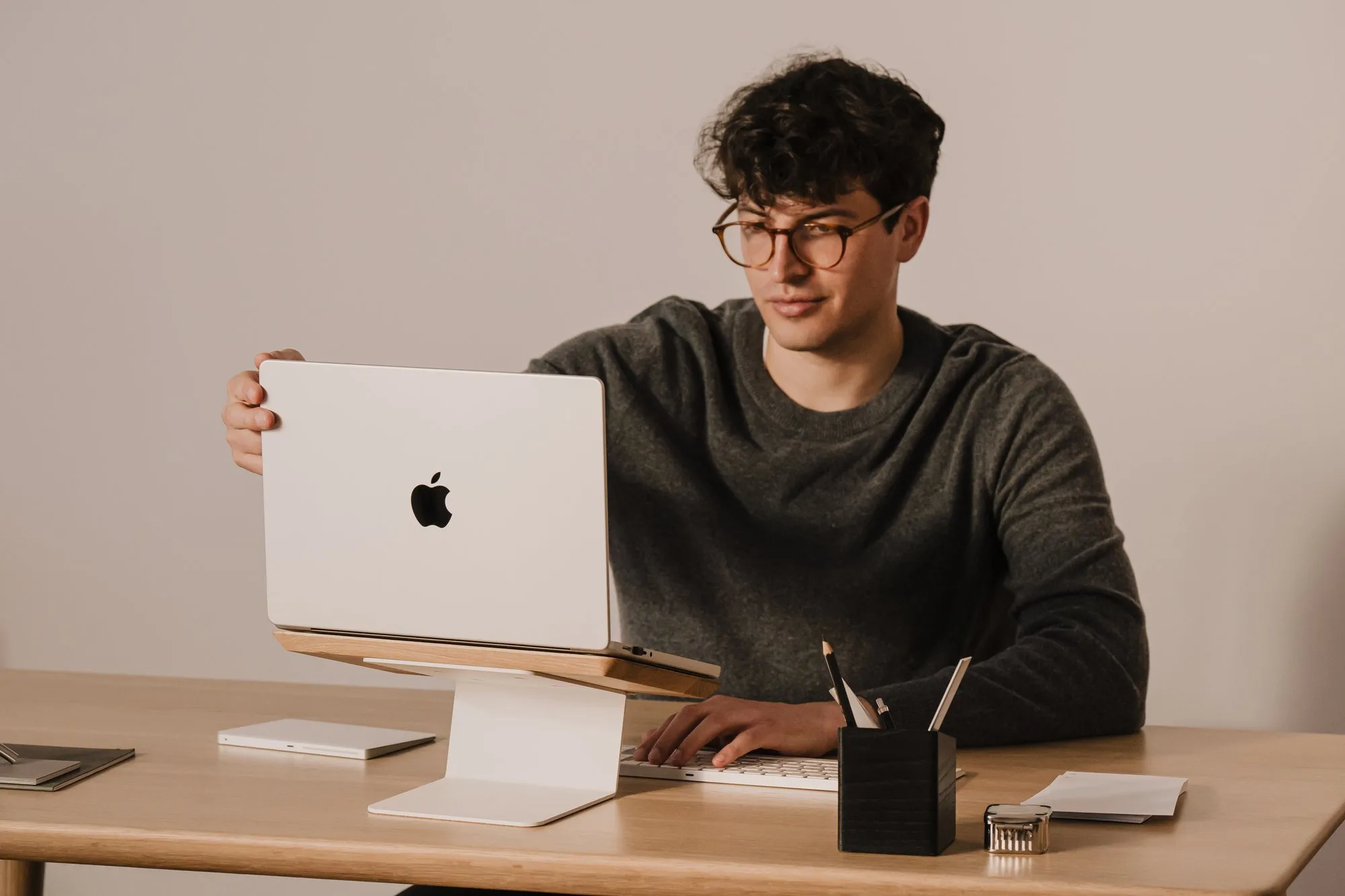 Man closing a laptop on a white and oak riser