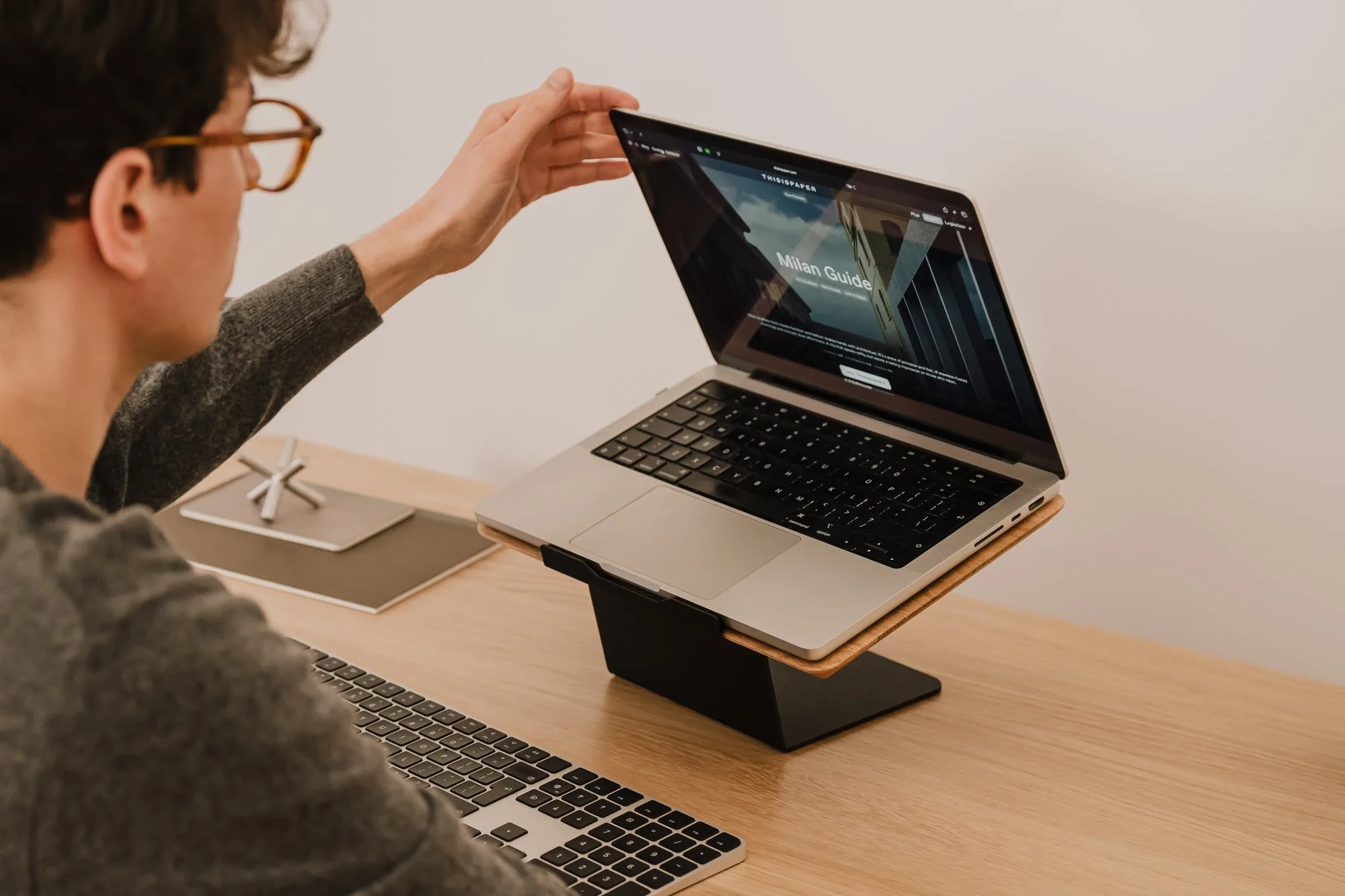 Man opening a laptop on a black riser