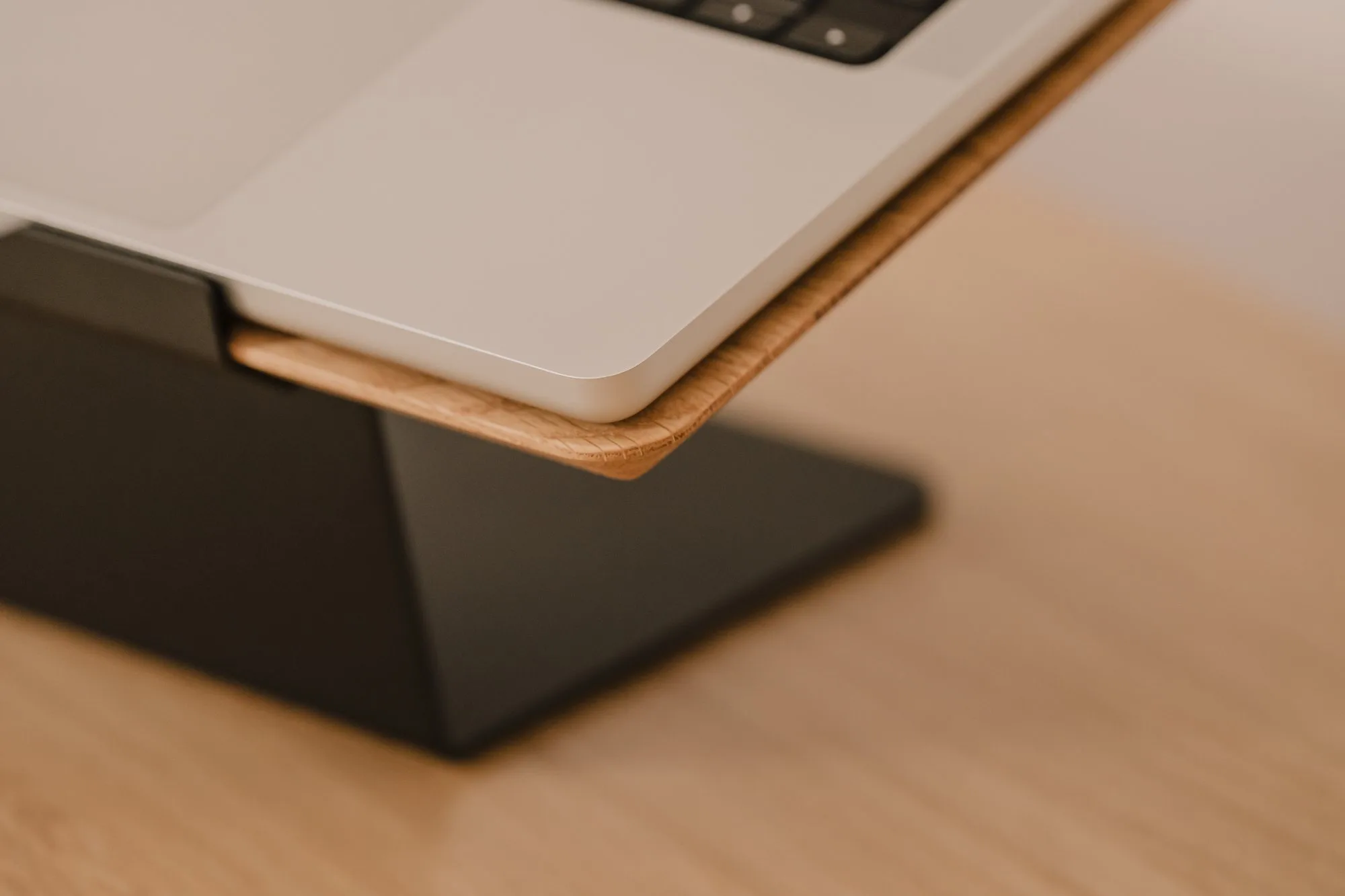 Close-up of a laptop edge on an oak top with a black base