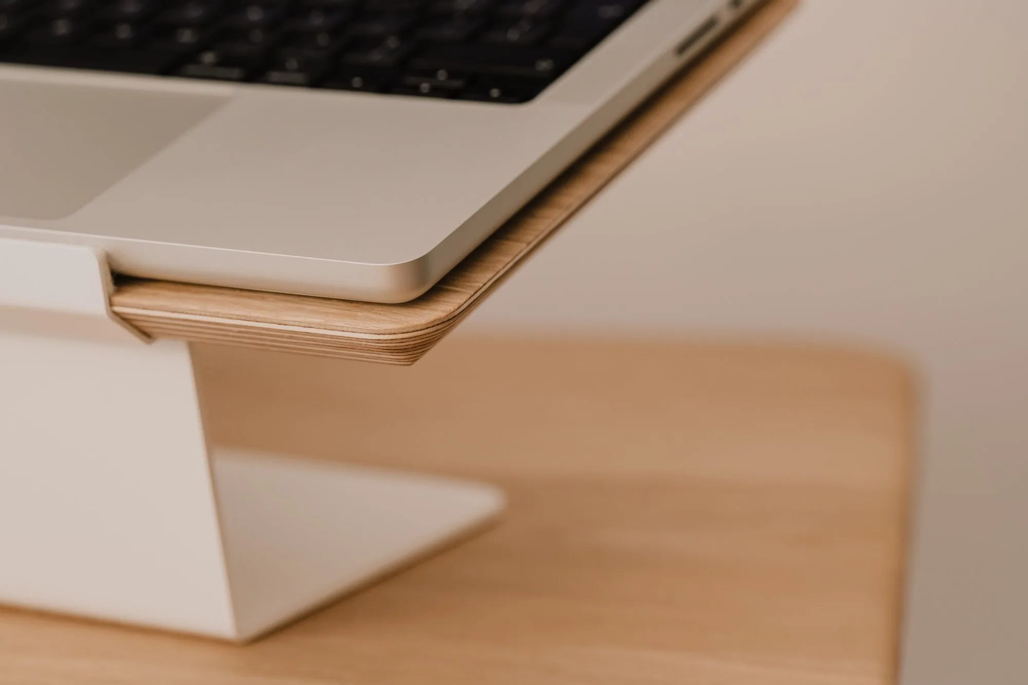 Close-up of a laptop edge on an oak top with a white base